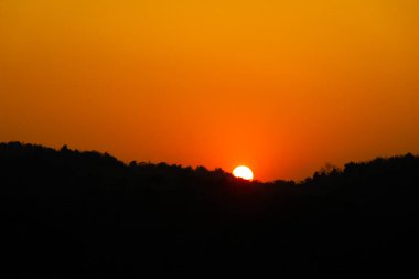 Orange Sun 'dan Sunset' e kadar dağın tepesinde ve uzak ağacın gölgesiyle nehri yansıtıyor. Huzurlu sakin yaşam arkaplan kopyalama alanı kavramı