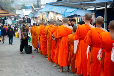 Kanchanaburi, Tayland - 20 Şubat 2021; Köylüler sabah Buda keşişlerine pirinç ve yiyecek verir. Rahip Monk ayıyla yürüyor tapınaktan şehire güzel geleneksel bir kültür olarak.