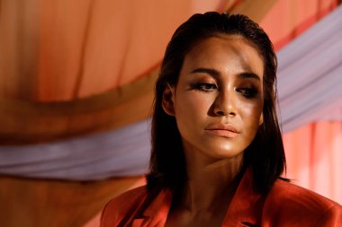 Moda güzeli Hintli kadının kısa siyah saçları var. Duygularını ifade ediyor. Asyalı bir kızın portresi öğleden sonra kırmızı ceket giyer. Pastel elbiselerin üzerine güneş gölgesi. Arka plan fotokopi alanı.