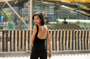 20 'li yaşlarda Asyalı bir kadının yarı vücut portresi düz siyah saç resmi bir elbise giyer. Kadın alışveriş için dışarıda dolaşmaktan mutlu.