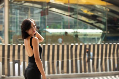 20 'li yaşlarda Asyalı bir kadının yarı vücut portresi düz siyah saç resmi bir elbise giyer. Kadın alışveriş için dışarıda dolaşmaktan mutlu.