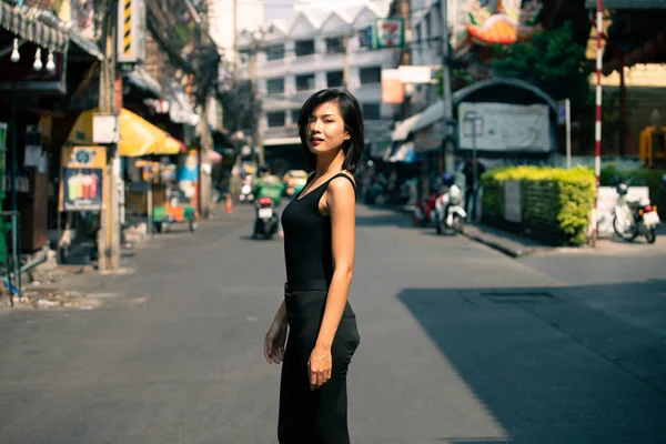 20 'li yaşlarda Asyalı bir kadının yarı vücut portresi düz siyah saç resmi bir elbise giyer. Kadın alışveriş için dışarıda dolaşmaktan mutlu.