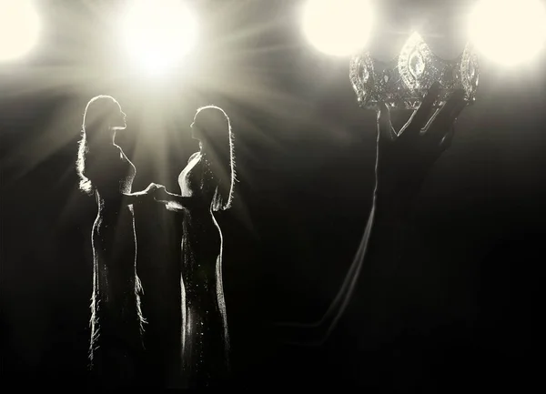 Her Kız Güzellik Yarışması Kraliçesi Yarışması 'nın hayalini kurar. Kadın savaş gemileri, Diamond Silver Crown 'u sahnede kazanan olarak yükseltiyor. Stüdyo ışıkları, arka plandaki ışıklı siluet.