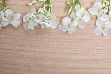 Tahta arka planda yeşil çubuklu yapay beyaz çiçek. Boşluğu kopyala, üst görünüm benzetimi metin ve logo için ayarlandı