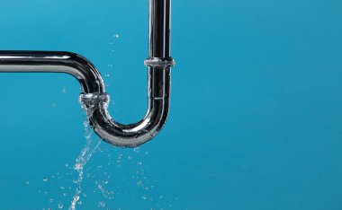 Lavabonun altındaki krom paslanmaz çelik borudan su sızdırıyor. Banyodaki borulardan su sızıyor ve su tıkanmış. Mavi banyo arka planı izole edildi