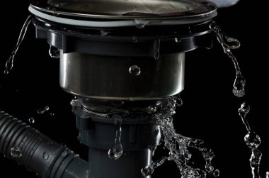 Tuvaletteki boru tesisatından sızan lavabo suyu damlaları tıkadı. Gri plastik boru lavabosundan sızan su. Siyah arkaplan izole