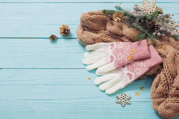 gloves, scarf  and christmas decorations on blue wooden background