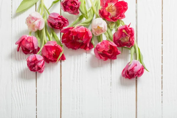 Beyaz ahşap zemin üzerinde kırmızı laleler