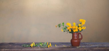 Vazodaki kasımpatılar eski ahşap masada.