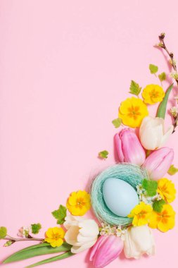 Pembe arka planda Paskalya yumurtaları ve bahar çiçekleri