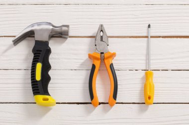 Beyaz ahşap arka planda pense, çekiç, tornavida.