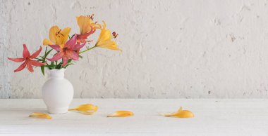 Beyaz arkaplanda beyaz vazodaki zambaklar