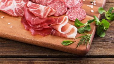 Ahşap masada çeşitli et ve sosisler var.