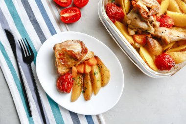 Patates, domates, havuç ve yabani otlarla pişirilmiş tavuk parçaları. Üst manzara, arka planda yan görünüm. Yakın plan ve orta plan. Metin için boşluk.