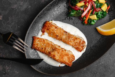 Kızarmış Barramundi veya Pangasius. Susam tohumlu ve limonlu ekşi kremalı balık bifteği. Avokado salatası ve kale yapraklı. sağlıklı beslenme tarzı