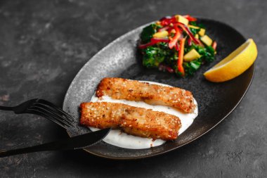 Kızarmış Barramundi veya Pangasius. Susam tohumlu ve limonlu ekşi kremalı balık bifteği. Avokado salatası ve kale yapraklı. sağlıklı beslenme tarzı