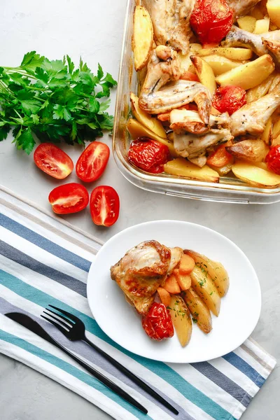 Patates, domates, havuç ve yabani otlarla pişirilmiş tavuk parçaları. Üst manzara, arka planda yan görünüm. Yakın plan ve orta plan. Metin için boşluk.
