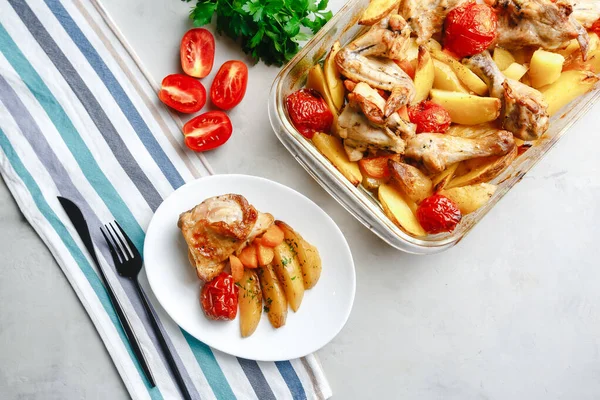 Patates, domates, havuç ve yabani otlarla pişirilmiş tavuk parçaları. Üst manzara, arka planda yan görünüm. Yakın plan ve orta plan. Metin için boşluk.