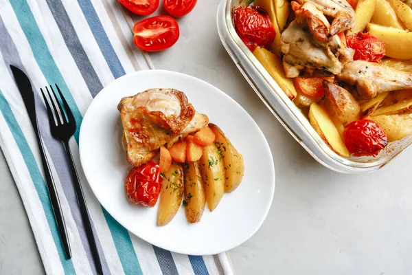 Patates, domates, havuç ve yabani otlarla pişirilmiş tavuk parçaları. Üst manzara, arka planda yan görünüm. Yakın plan ve orta plan. Metin için boşluk.