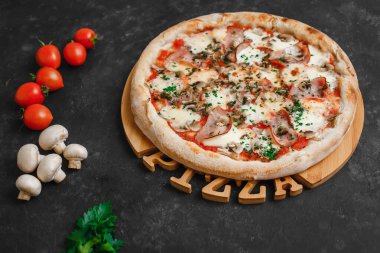 Jambonlu ve mantarlı ev yapımı pizza, domates sosu, mozzarella peyniri ve koyu arkaplanda otlar. Üst görünüm, yan görünüm