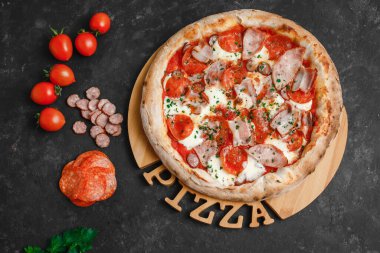 Jambonlu, sucuklu, pastırmalı, füme sosisli ve koyu otlu ev yapımı pizza. Üst görünüm, yan görünüm