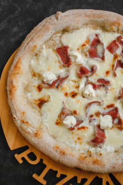 Pastırma soslu ev yapımı pizza, mozzarella ve siyah arka planda ricotta. Üst görünüm, yan görünüm