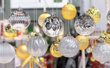Altın ve gümüş Noel topları ipliklerde sallanıyor.