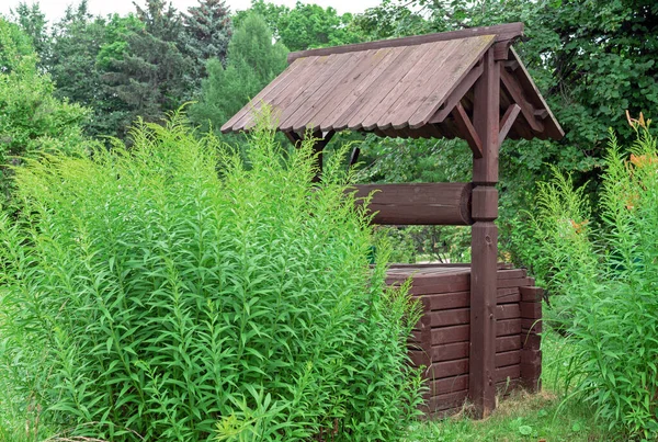 緑の植生の真ん中にあるロシアの村の古い木造井戸 — ストック写真