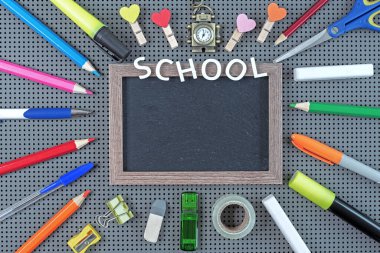 Çerçeveli siyah tebeşir tahtası etrafında çeşitli okul malzemeleri. Okul kavramı.