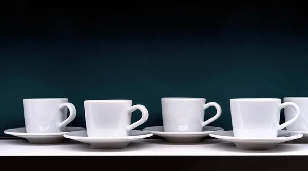 Koyu Yeşil Arka Planda Çay Tabakları Olan Beyaz Kahve Fincanları — Stok fotoğraf
