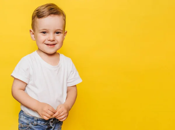 Retrato de un lindo niño riéndose sobre un fondo amarillo. Copiar espacio. — Foto de Stock