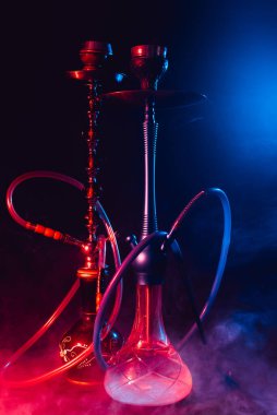 Modern nargile, dumanlı siyah arka planda neon ışıklı shisha.