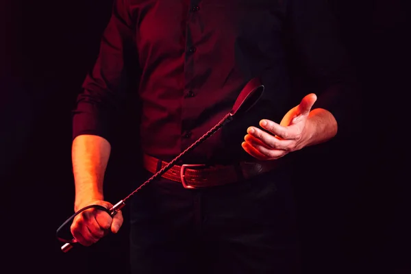 Mão masculina segurando chicote de couro preto. flogger — Fotografia de Stock