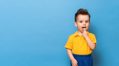 Lolipopu olan bebek mavi bir duvar arkasında duruyor. Çocukluk kariyerlerinin önlenmesi. Boşluğu kopyala