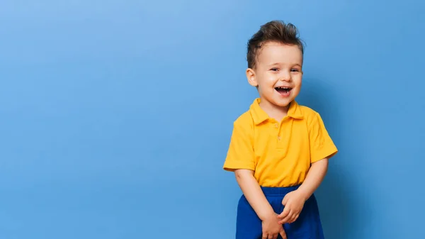 Retrato de um menino rindo bonito em um fundo azul. Espaço de cópia. — Fotografia de Stock