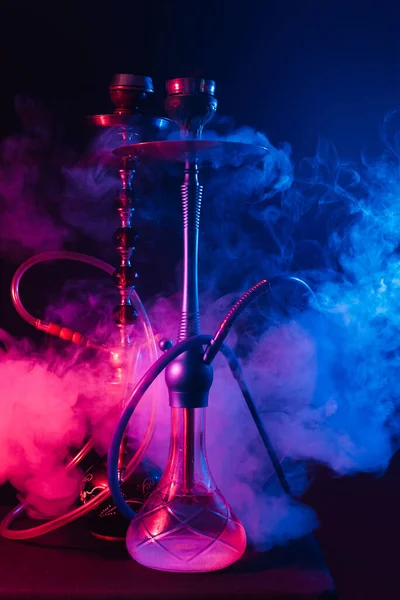 Fashionable hookah with a cloud of smoke on a black background with red and blue glow — Stock Photo, Image