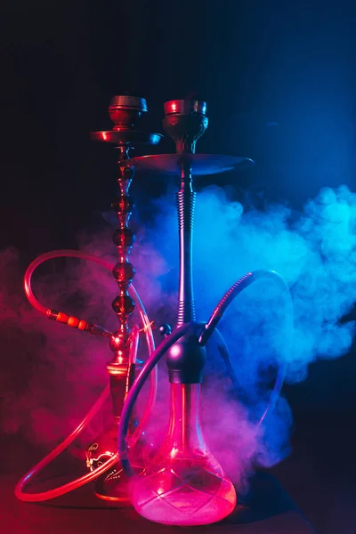 Modern hookah, shisha on a smoky black background with neon lighting — Stock Photo, Image