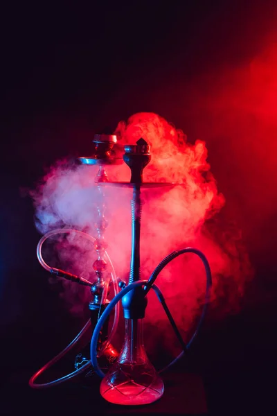 Fashionable hookah with a cloud of smoke on a black background with red and blue glow — Stock Photo, Image