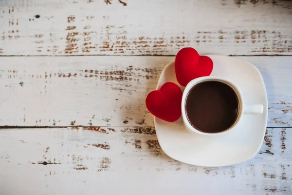 Κόκκινες καρδιές και ένα φλιτζάνι καφέ σε λευκό ξύλινο φόντο. — Φωτογραφία Αρχείου