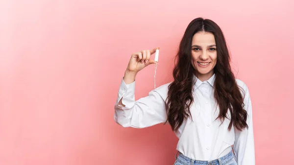 Eine junge Frau hält einen Menstruationsabstrich in ihren Händen. Rosa Hintergrund. Raum für Text. Das Konzept der weiblichen Hygiene. — Stockfoto