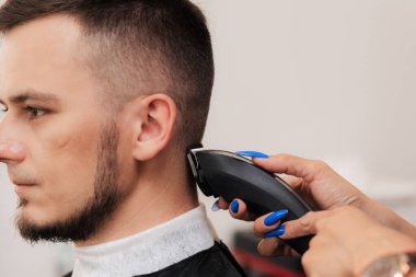 Berber bir kadın makaslı genç bir adam için saç tıraşı yapar. Yakın plan.