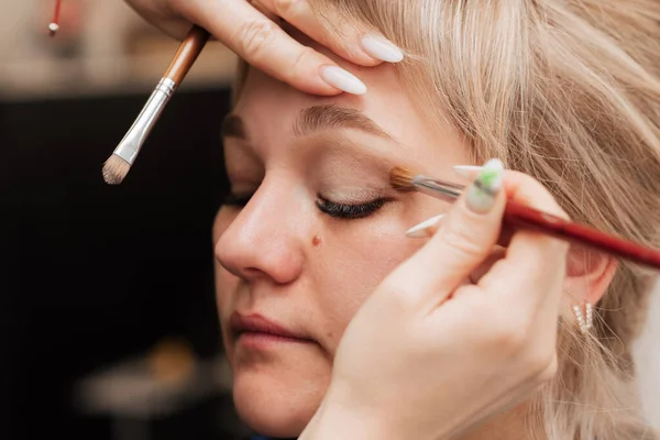 Een vrouwenhand brengt oogschaduw aan met een make-up borstel. — Stockfoto