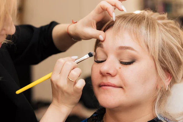 Uma mão de mulher se aplica e tonifica a sombra dos olhos com uma escova de maquiagem. — Fotografia de Stock