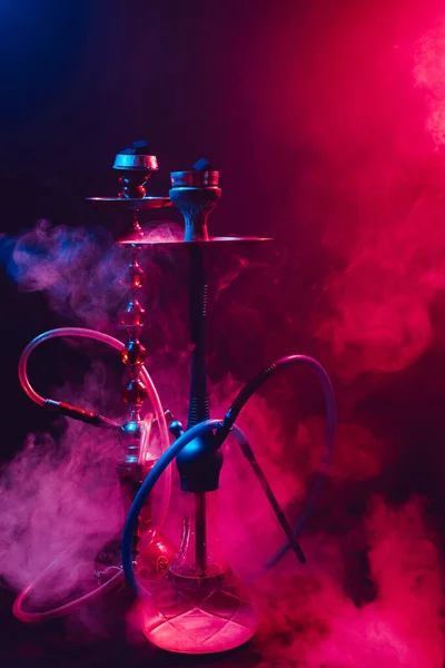 Fashionable hookah with a cloud of smoke on a black background with red and blue glow — Stock Photo, Image