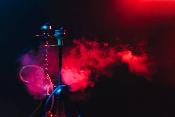 Nowoczesny hookah, shisha na dymiącym czarnym tle z neonowym oświetleniem i dymem. Miejsce na tekst — Zdjęcie stockowe