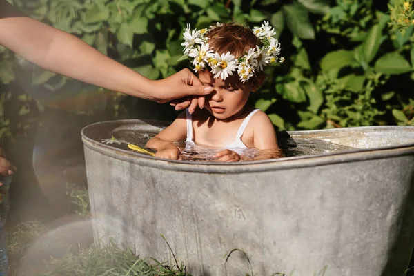 Las mamás limpian la suciedad de la nariz de una niña que se baña en el baño en el jardín. —  Fotos de Stock