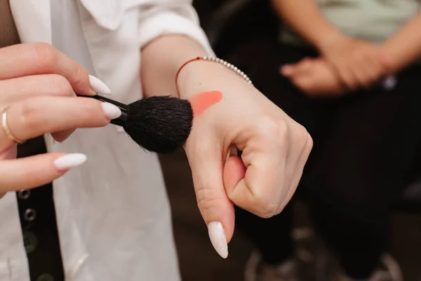 A filmar num salão de beleza. Uma imagem das mãos de um maquiador que está digitando um produto cosmético com um pincel. — Fotografia de Stock