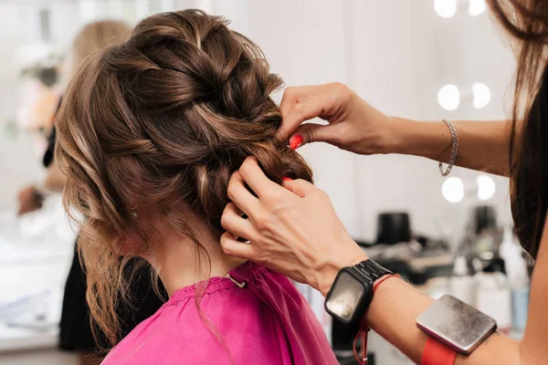 Una chica-peluquera hace un peinado de clientes para la celebración fijando las hebras con horquillas y horquillas. —  Fotos de Stock