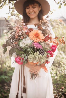 Güzel bir kadın elinde bir buket çiçek ve bitki tutuyor. Romantik ruh hali