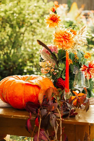 Herbstromantik: Bouquet aus Dahlien, Granatäpfeln, Kerzen, Kürbissen und Gläsern — Stockfoto